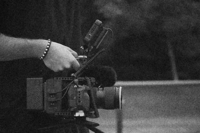 Gros plan sur une caméra de cinéma équipée, tenue à la poignée pendant un tournage