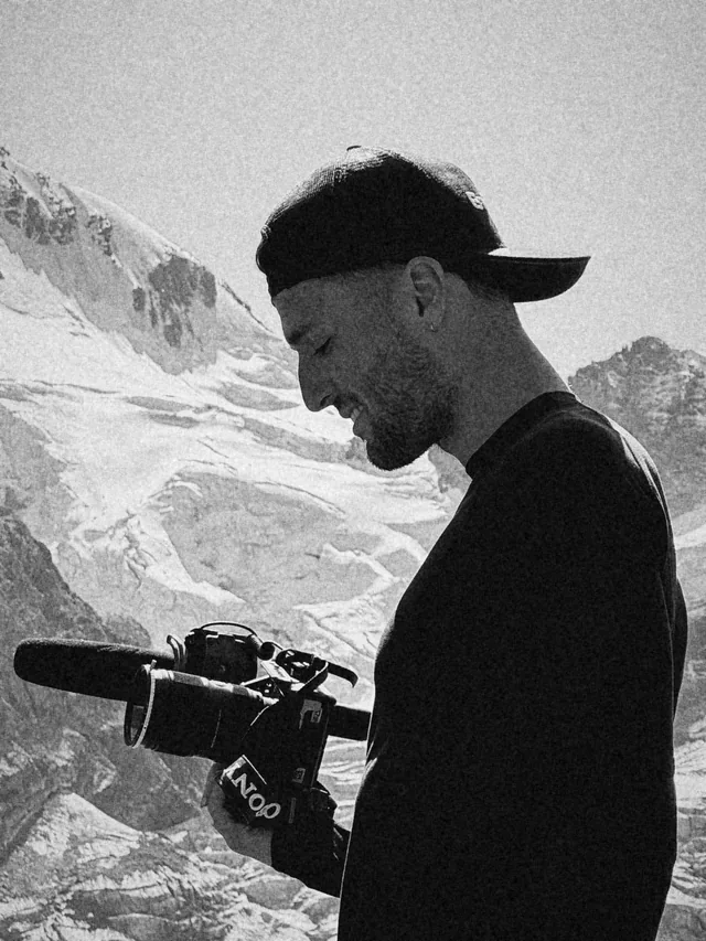 Victor Cazaubon, fondateur de WATT Production, caméra et micro à la main devant un glacier