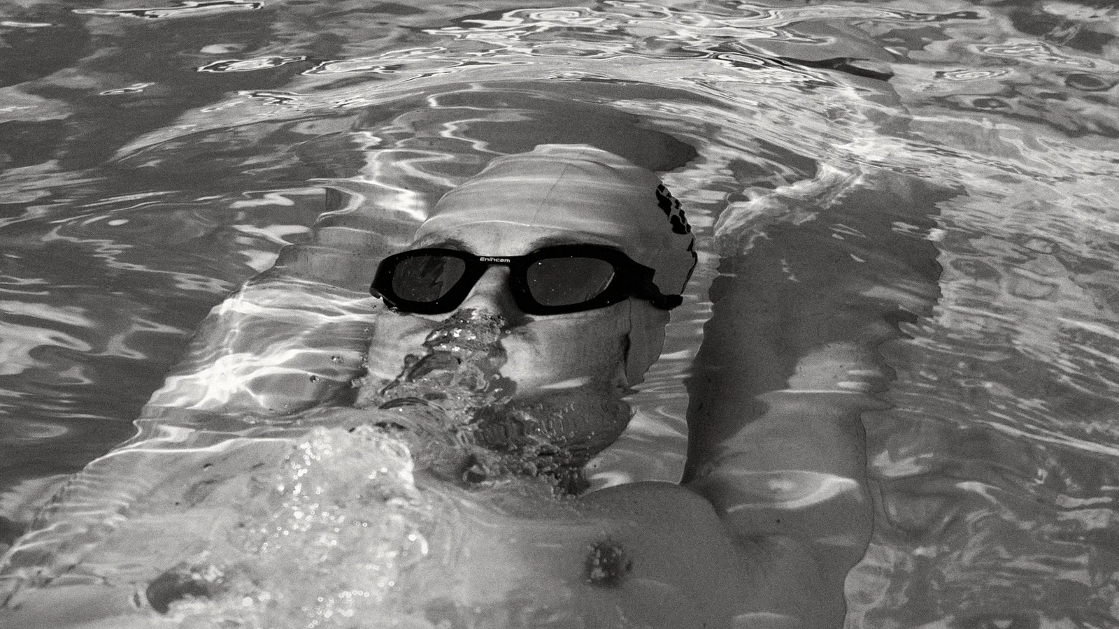 Nageur sur le dos avec des lunettes Enihcam, reflets de lumière dans l’eau, en noir et blanc